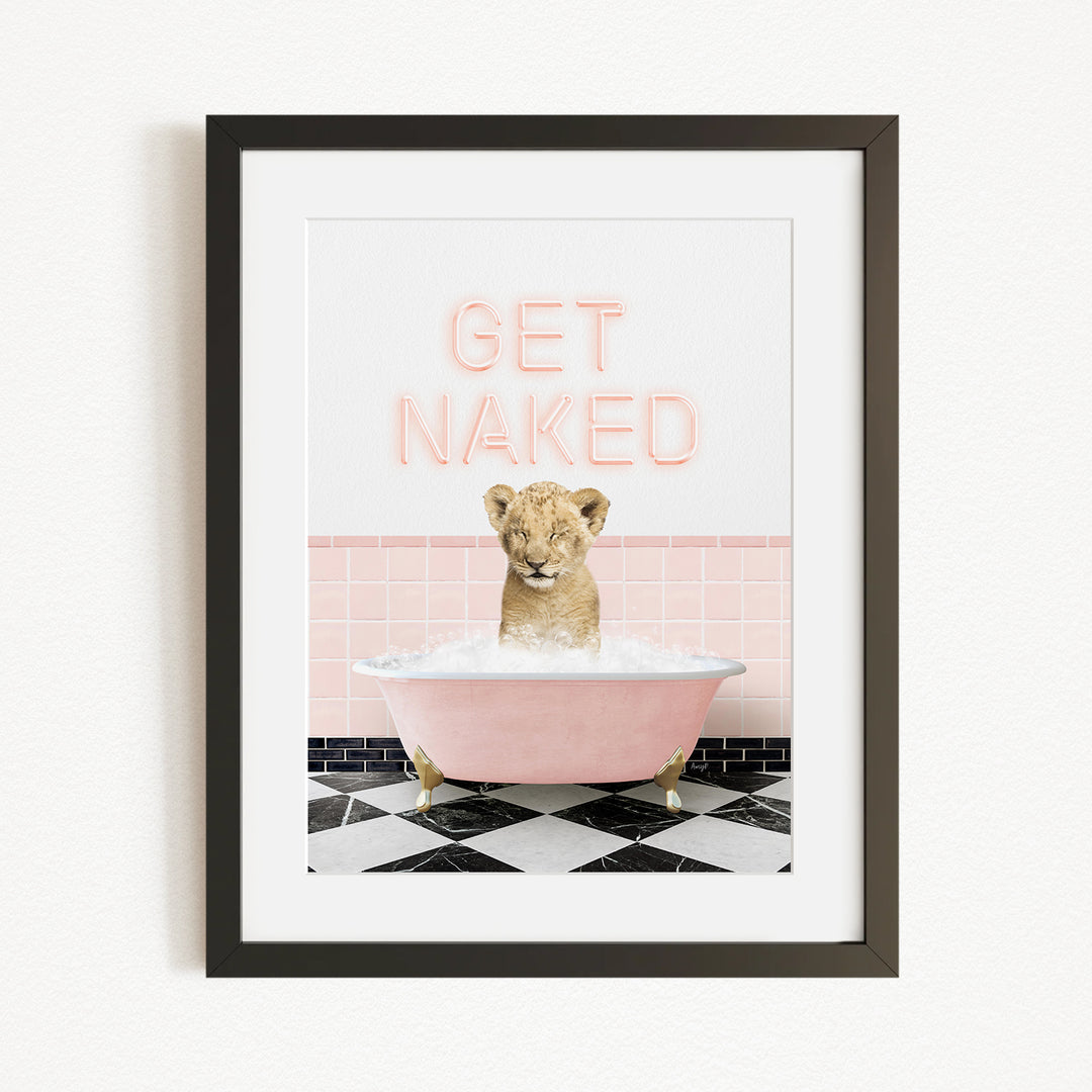 A framed image depicting a young lion cub sitting in a pink bathtub filled with water, with the text "GET NAKED" displayed above it.