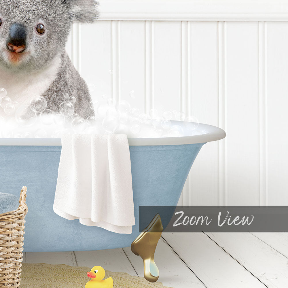 A koala bear sitting in a blue bathtub filled with bubbles, surrounded by a yellow rubber duck and a white basket.