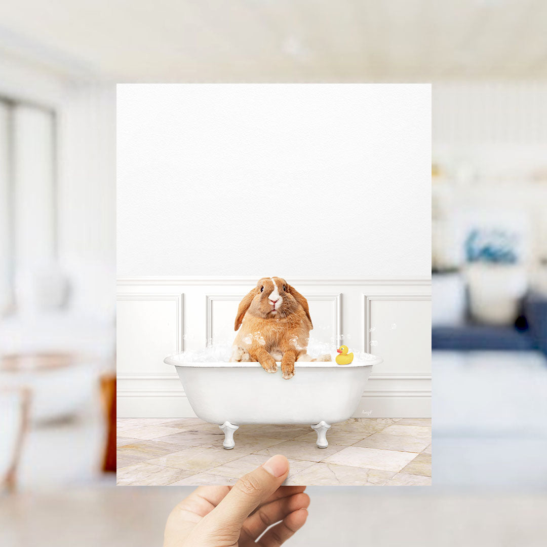 A brown rabbit sitting in a white bathtub filled with bubbles, with a yellow rubber duck floating nearby.