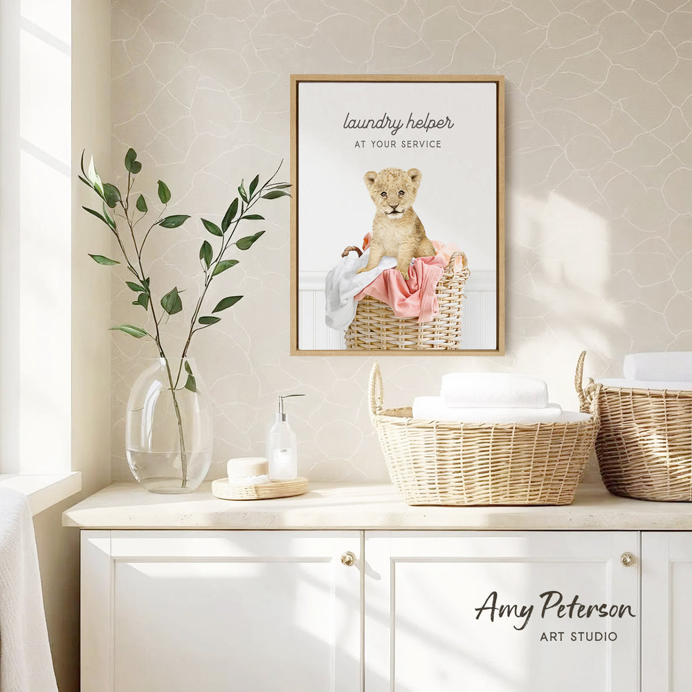 a framed poster of a baby lion sitting in a basket, hanging on a wall above a white cabinet with baskets.