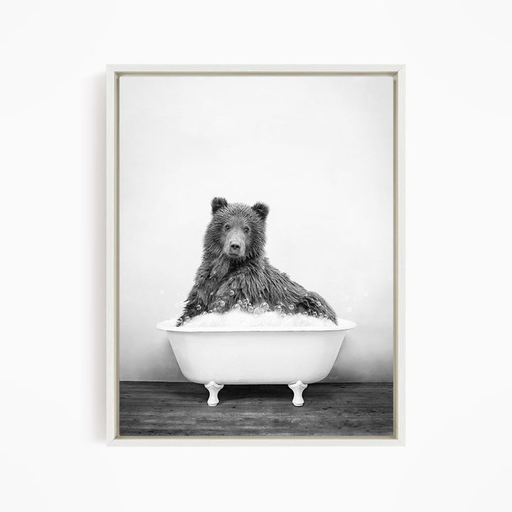 A black and white image of a bear sitting in a bathtub filled with bubbles.