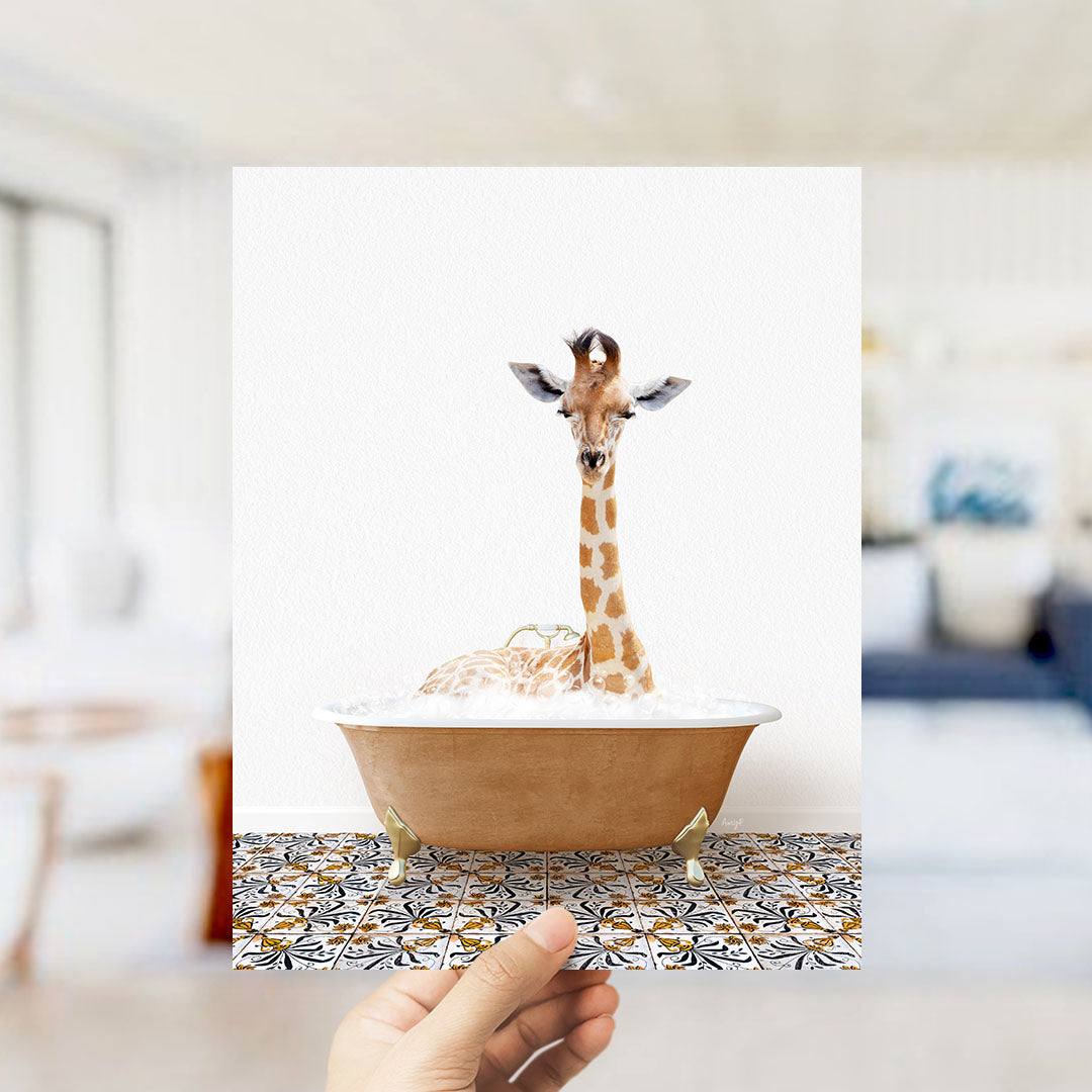 A giraffe sitting in a bathtub filled with bubbles, with a hand holding the photo up to the camera.