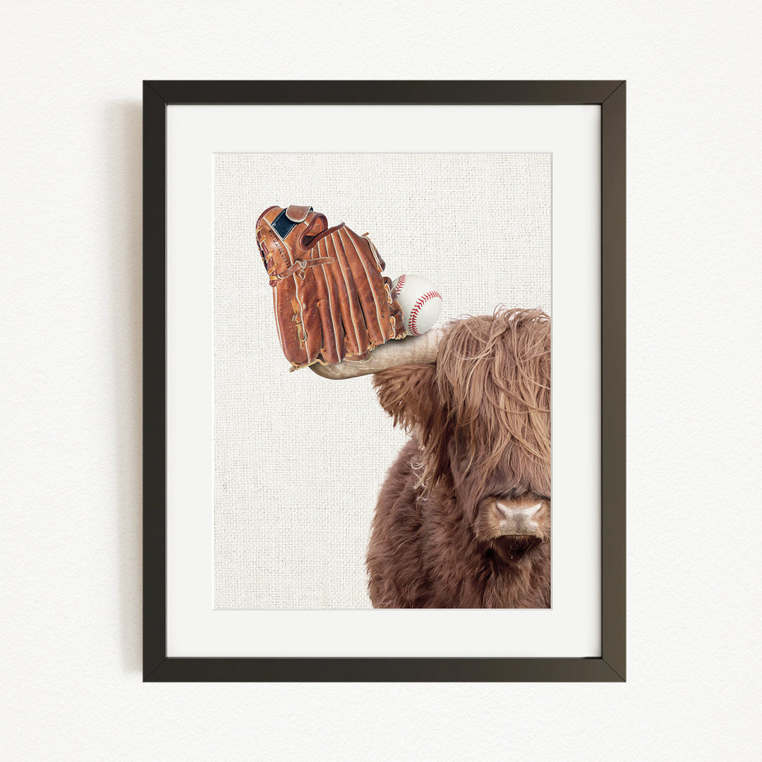 A framed image depicting a cow with a baseball glove on its head.