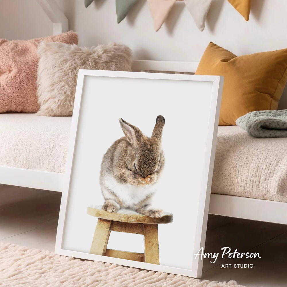 A framed image of a rabbit sitting on a wooden stool, with a cozy and inviting atmosphere in the background.