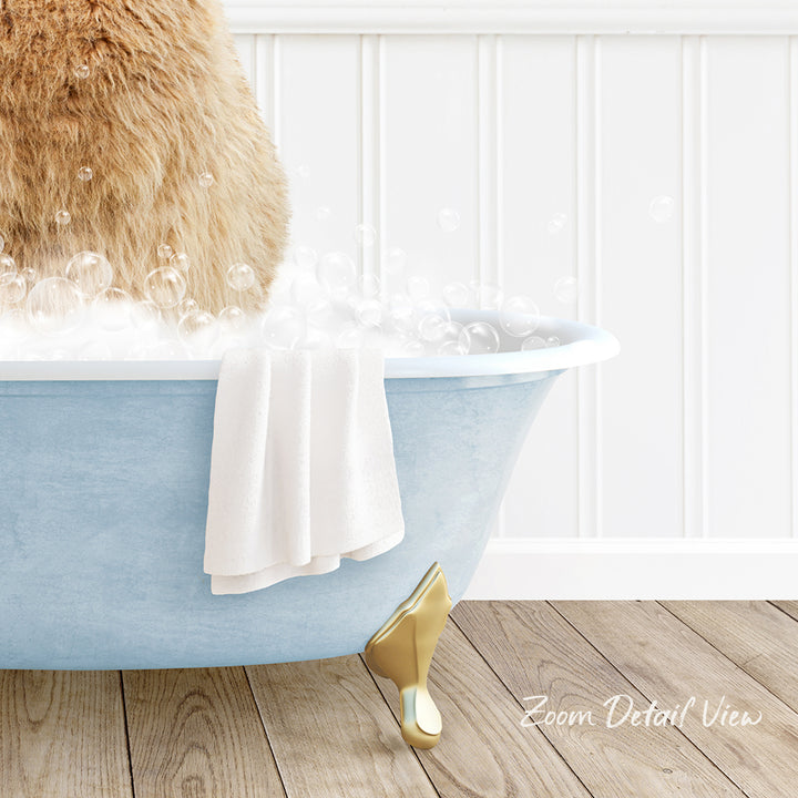 A fluffy brown cat is sitting in a blue bathtub filled with bubbles, with a white towel and gold bathtub leg visible.