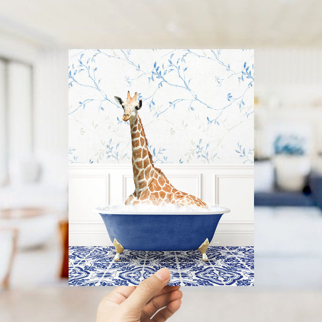 A giraffe sitting in a blue bathtub filled with bubbles, surrounded by a blue and white floral patterned wall.