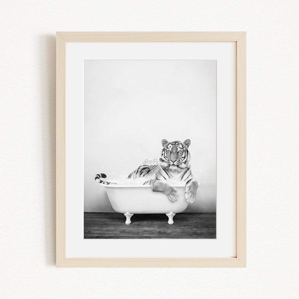 A black and white photograph of a tiger sitting in a bathtub, with its head resting on the edge of the tub.