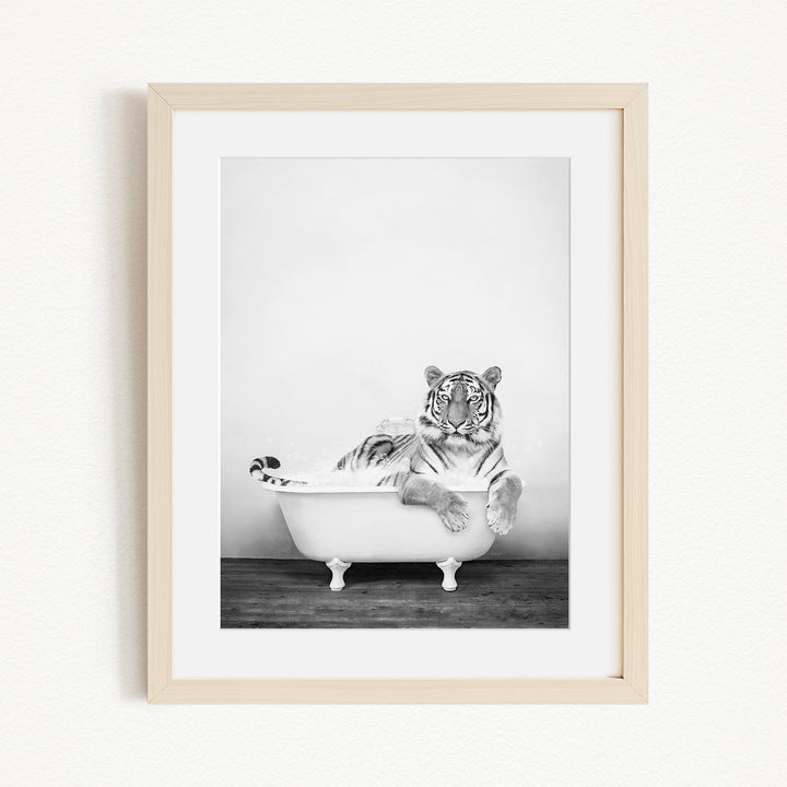 A black and white photograph of a tiger sitting in a bathtub, with its head resting on the edge of the tub.