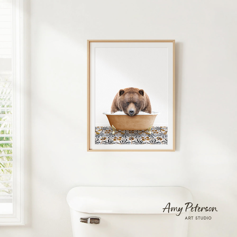 A framed image of a brown bear sitting in a bowl of water, with a patterned mat on the floor below.