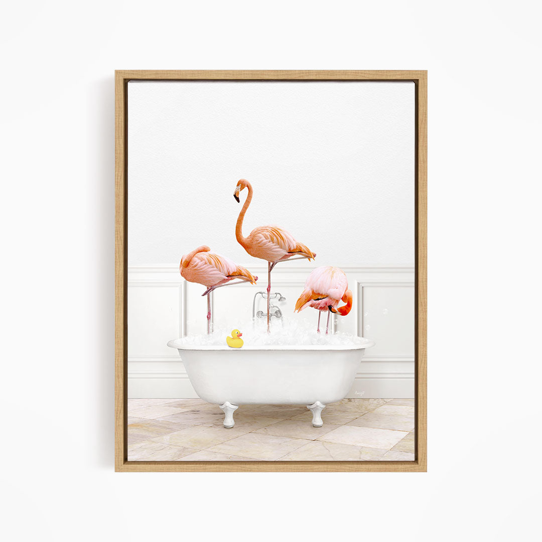 A framed image depicting three flamingos standing in a white bathtub filled with water, with a yellow rubber duck floating in the water.