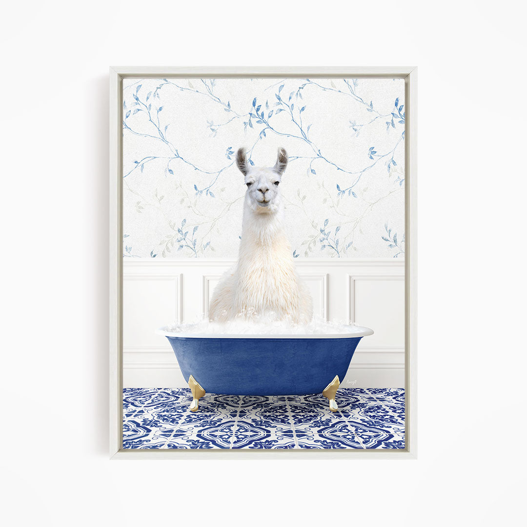 A white llama sitting in a blue bathtub filled with bubbles, surrounded by a blue and white patterned tile floor.