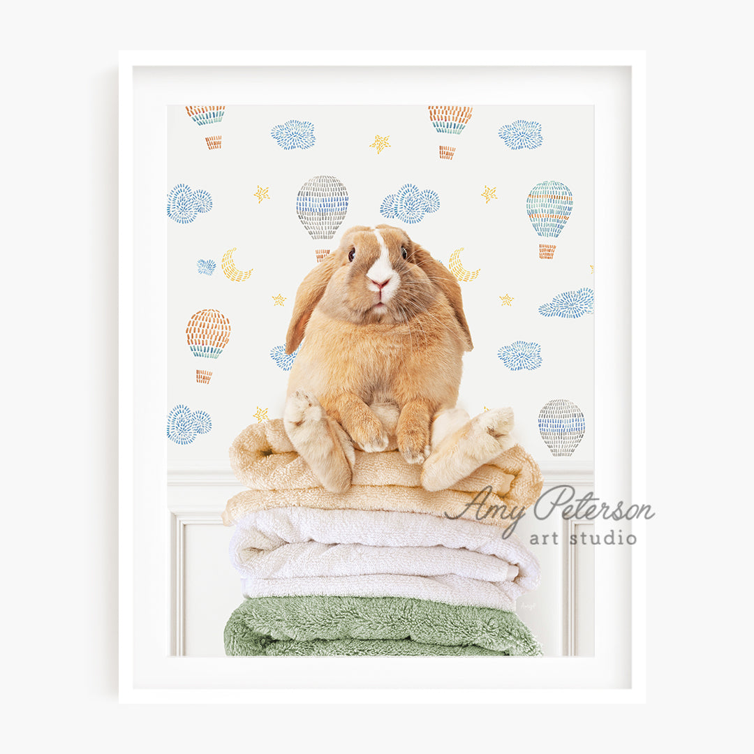 a rabbit sitting on top of a stack of towels