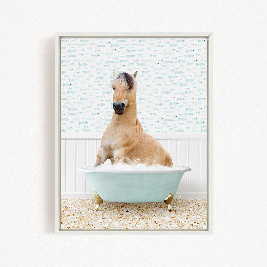 A light brown horse is sitting in a light blue bathtub filled with water, surrounded by a pattern of small fish on the wall behind it.