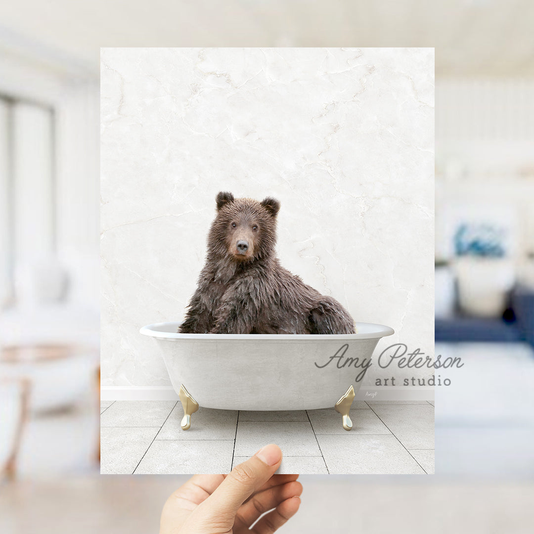 a hand holding up a polaroid picture of a bear in a bathtub