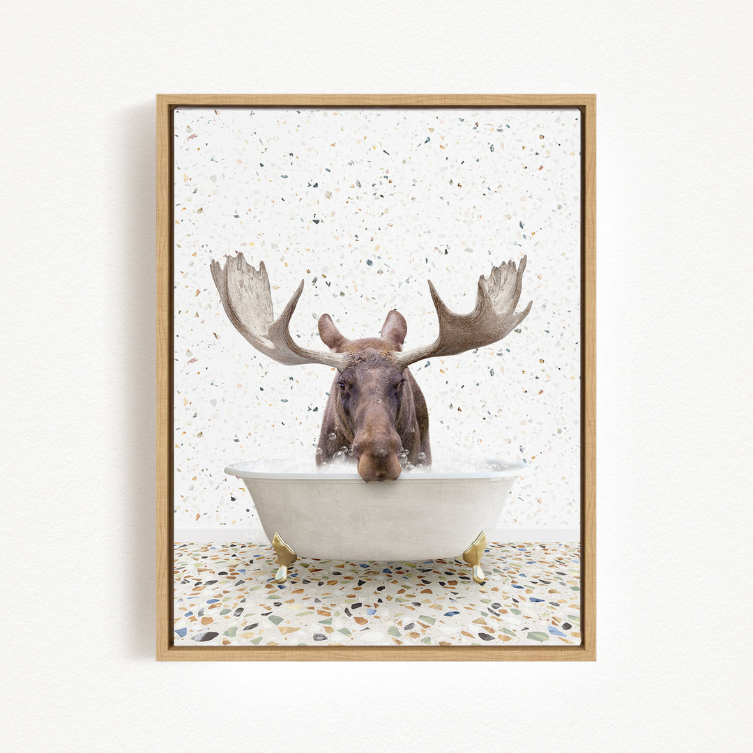 A moose with large antlers is sitting in a bathtub filled with water, surrounded by a speckled tiled floor.