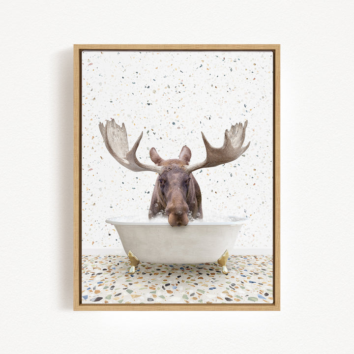 A moose with large antlers is sitting in a bathtub filled with water, surrounded by a speckled tiled floor.