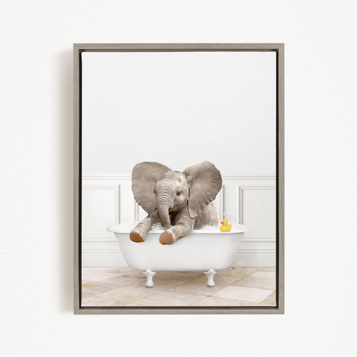 A gray elephant is sitting in a white bathtub, with a yellow rubber duck floating on the water.