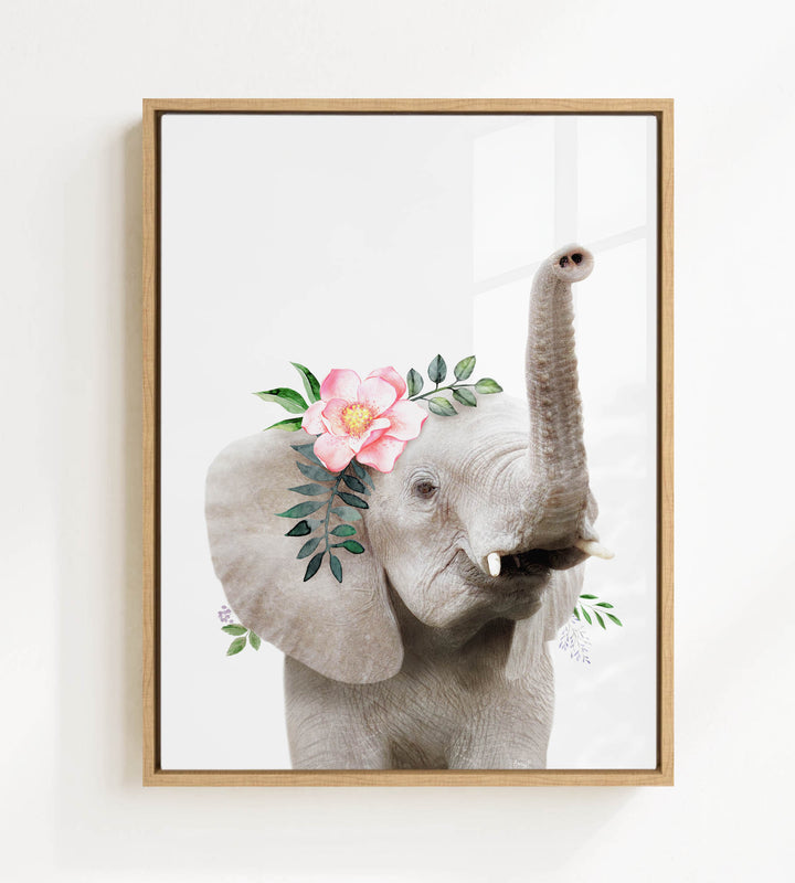 A framed image of an elephant with a pink flower on its head and green leaves.