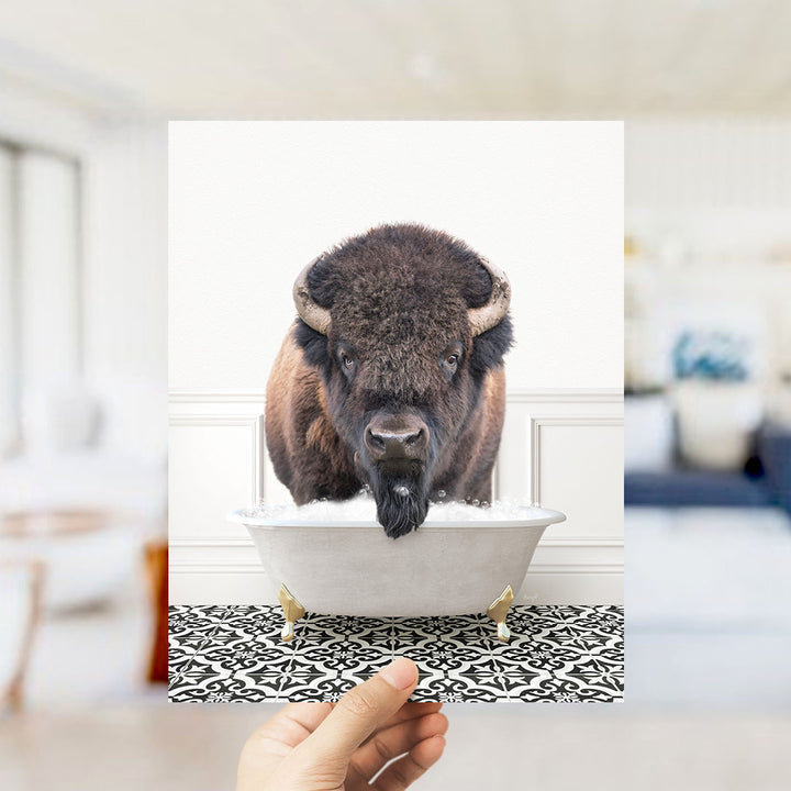 A buffalo with large horns is sitting in a white bathtub filled with water, creating a humorous and unexpected scene.