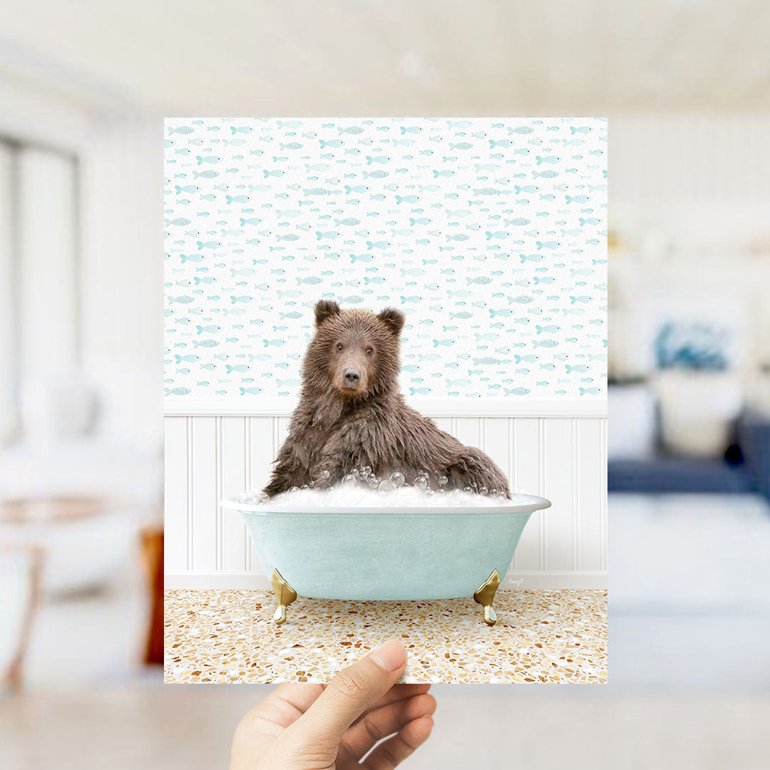 A brown bear sitting in a light blue bathtub filled with bubbles, surrounded by a pattern of fish.