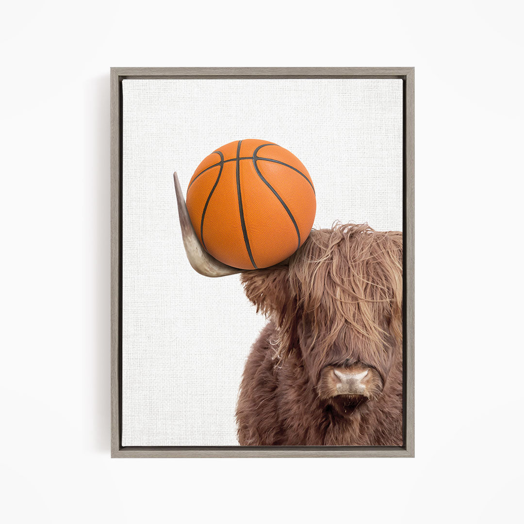 A brown cow with long hair is holding a basketball on its head.