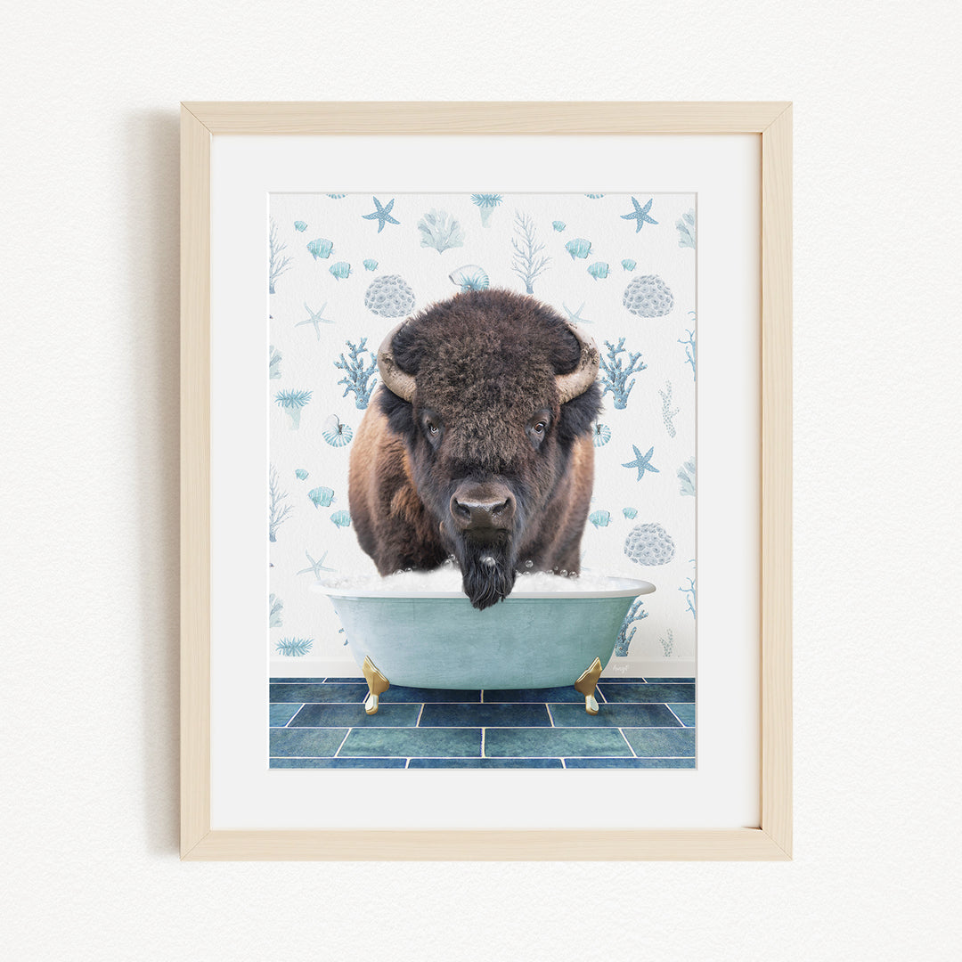 A framed image depicting a bison standing in a bathtub filled with water, surrounded by a blue and white floral pattern.