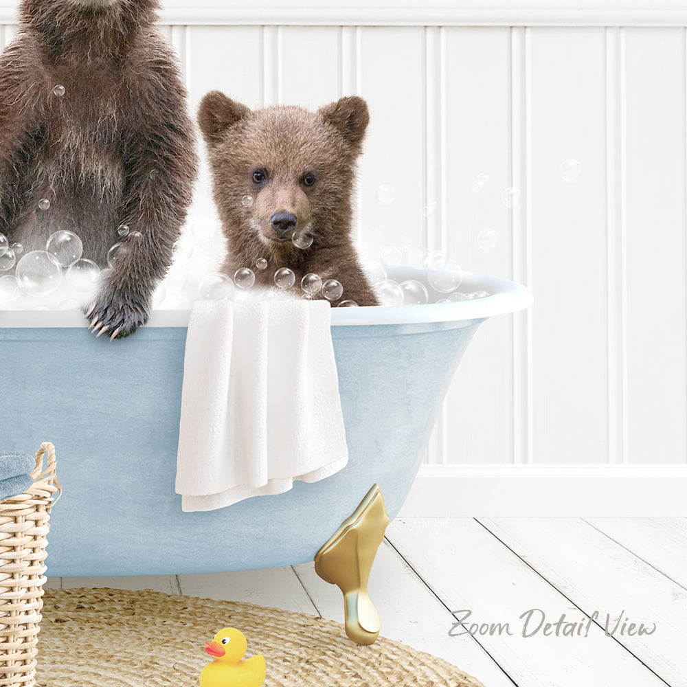 A baby bear sitting in a bathtub filled with bubbles, with a yellow rubber duck nearby.