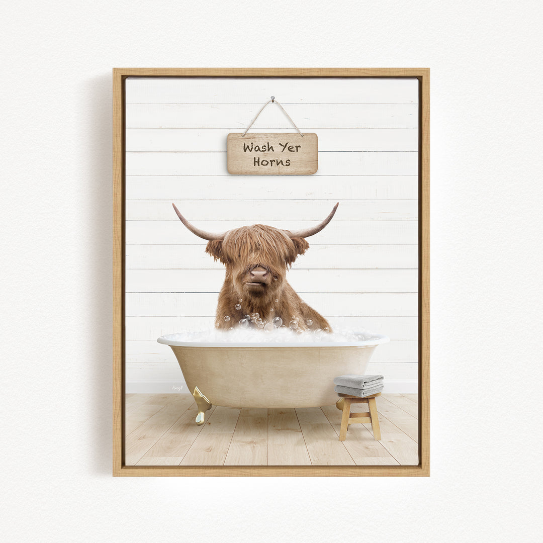 A brown cow with horns is sitting in a bathtub filled with bubbles, with a sign above that says "Wash Your Horns".