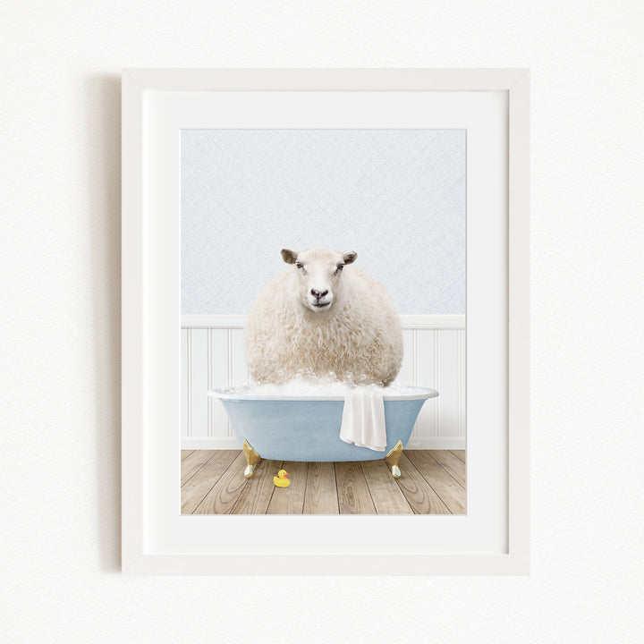 A fluffy white sheep sits in a blue bathtub filled with bubbles, surrounded by yellow rubber duckies.
