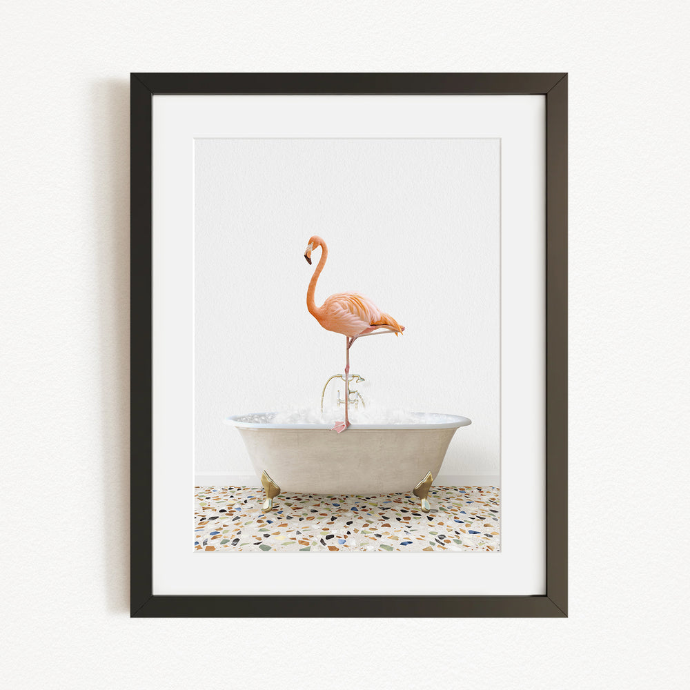 A framed image of a flamingo standing on one leg inside a white bathtub.