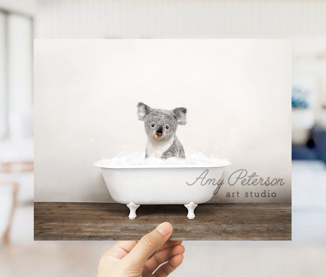 a hand holding up a photo of a koala in a bathtub