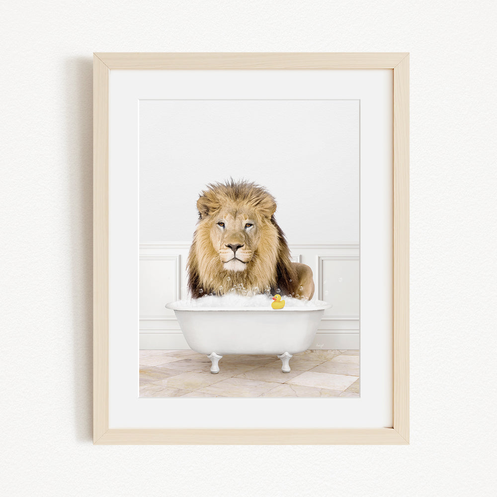 A lion sitting in a white bathtub filled with water and bubbles, with a yellow rubber duck floating in the water.