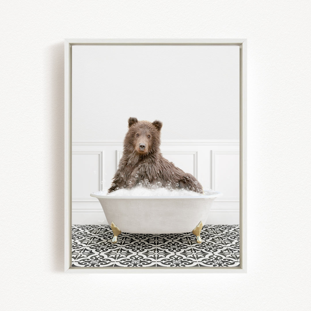 A brown bear sitting in a white bathtub filled with bubbles, surrounded by a black and white patterned floor.