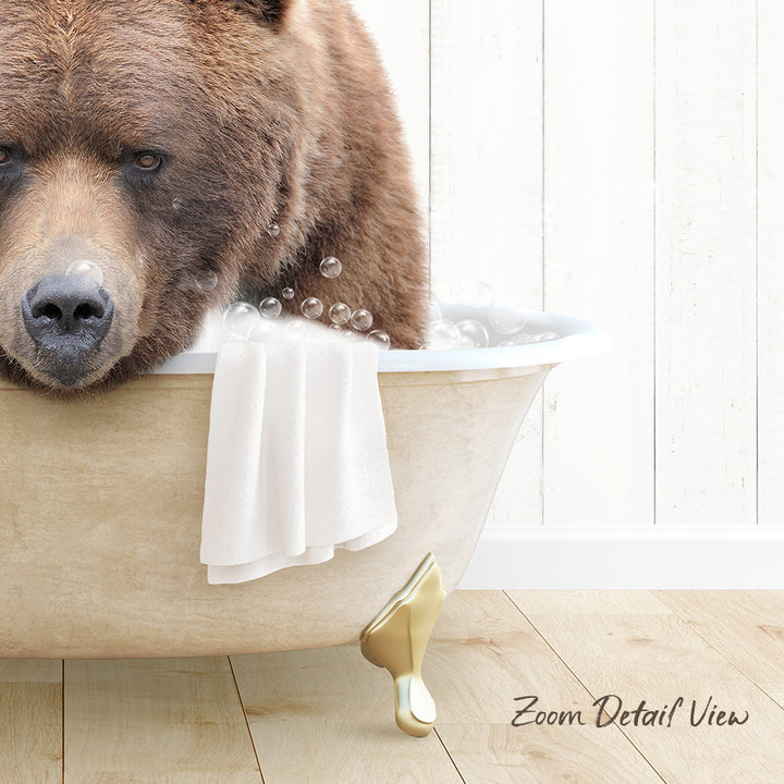 A brown bear sitting in a bathtub filled with bubbles, with a towel draped over the side.
