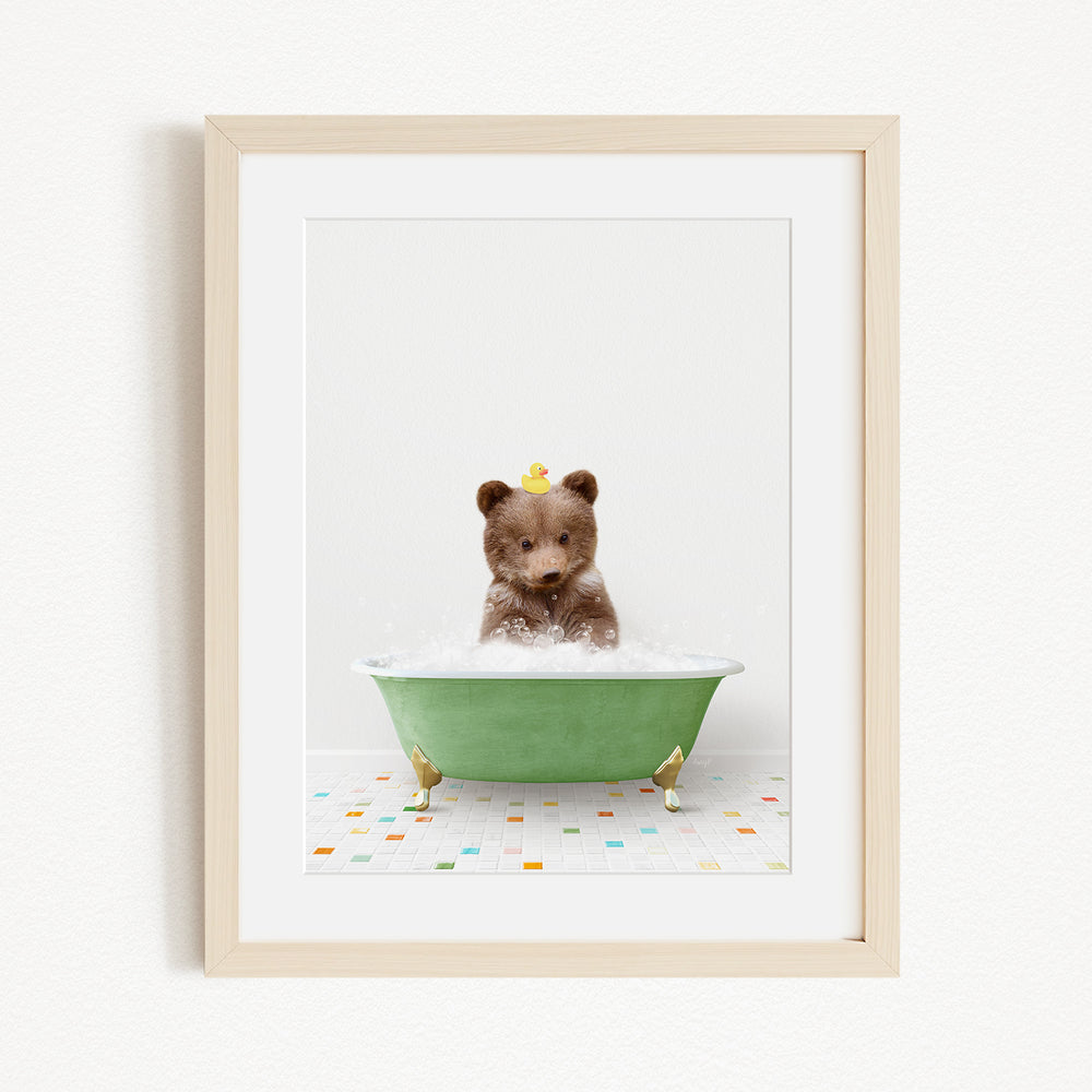 A brown bear sitting in a green bathtub filled with bubbles, with a yellow rubber duck floating on the water.