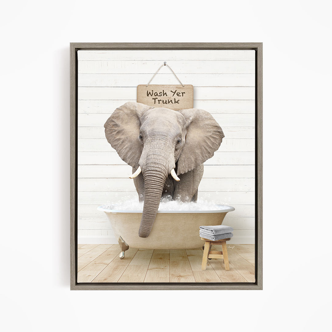 A gray elephant is sitting in a bathtub filled with water, with a sign above it that says "Wash Yer Trunk".