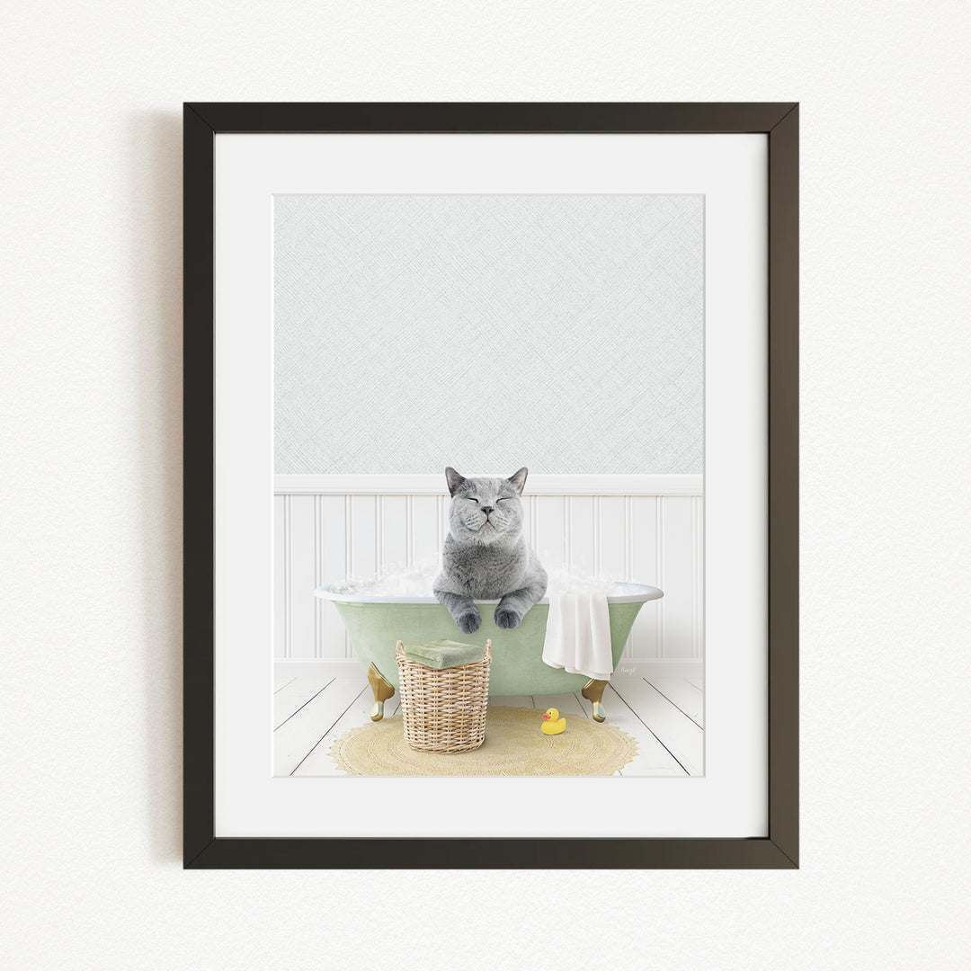 A gray cat sitting on a green bathtub, with a basket of rubber ducks and a towel nearby, in a bathroom setting.