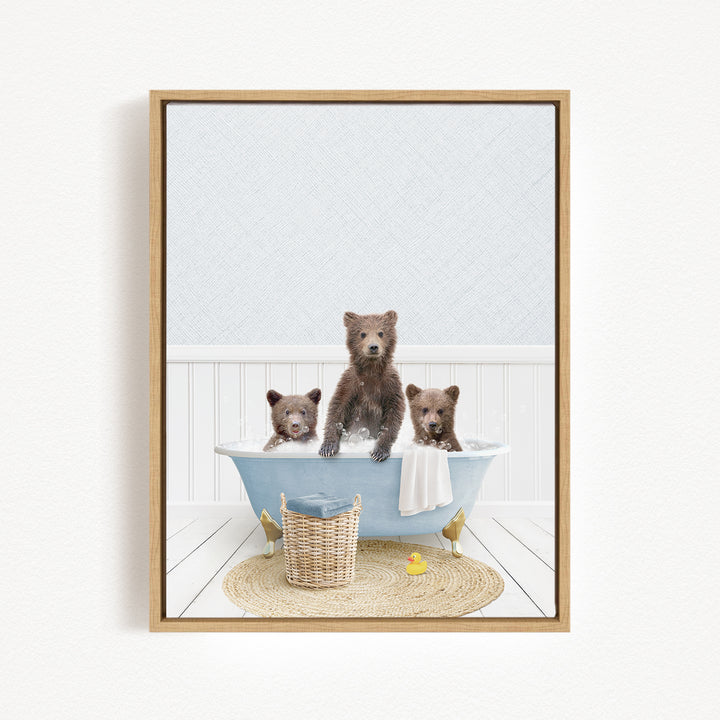 A framed image depicting three brown bears sitting in a blue bathtub, with a yellow rubber duck floating in the water.