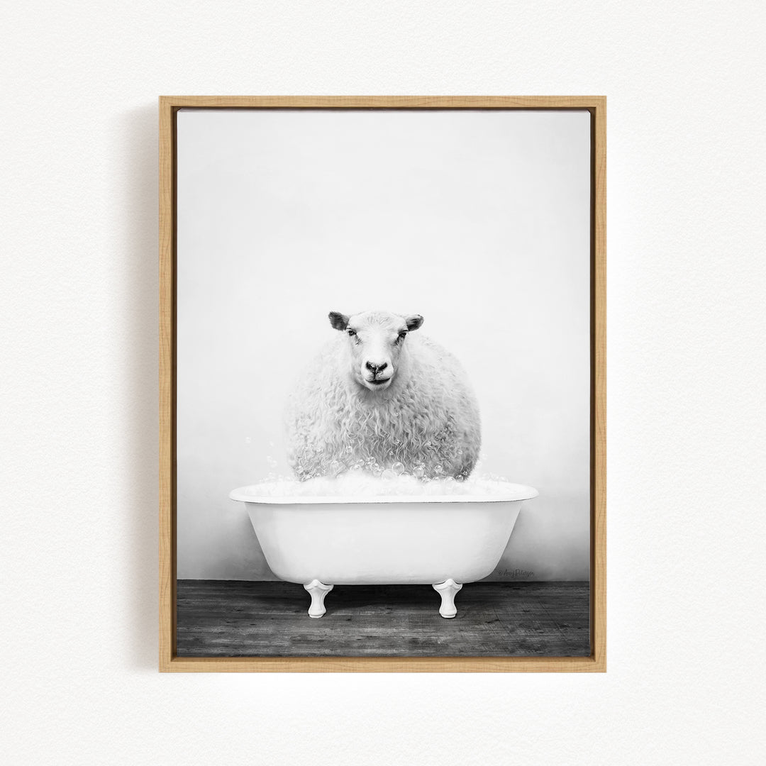 A fluffy white sheep sits in a white bathtub filled with bubbles, looking directly at the camera.