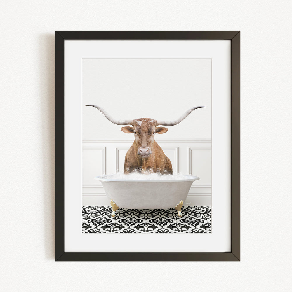 A framed image of a horned animal, likely a cow or a bull, sitting in a bathtub filled with water, creating a whimsical and humorous scene.