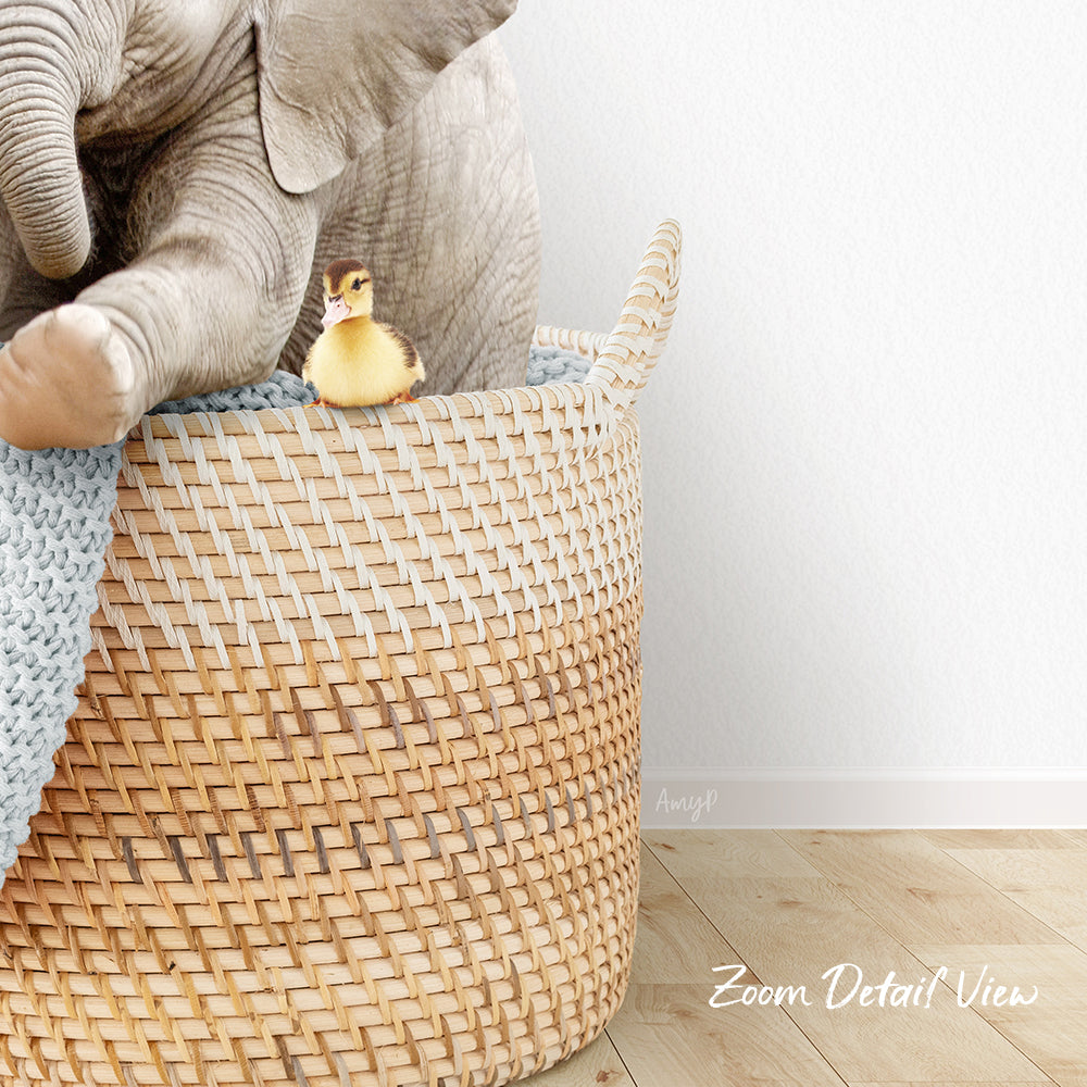 A small yellow duck sits in a woven basket, with a larger elephant trunk resting on the basket.