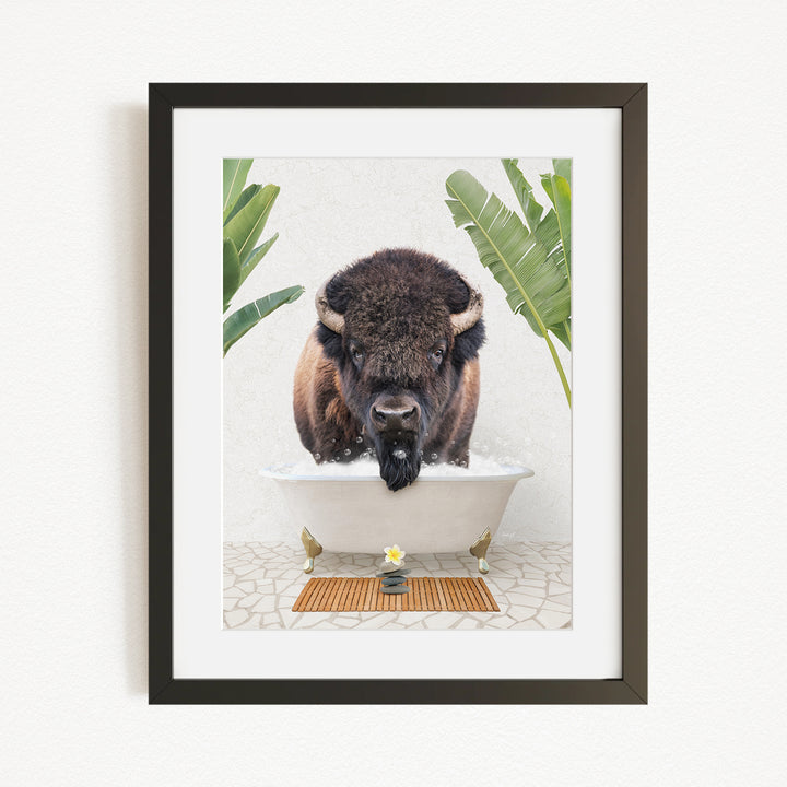 A buffalo is standing in a bathtub filled with water, surrounded by tropical plants and a wooden mat on the floor.
