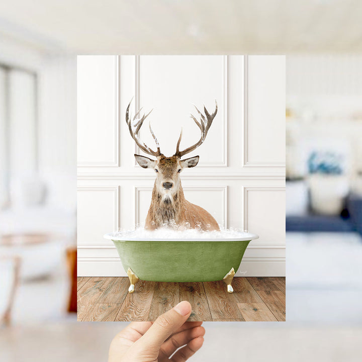 A deer with large antlers is sitting in a green bathtub filled with water, creating a whimsical and unexpected scene.