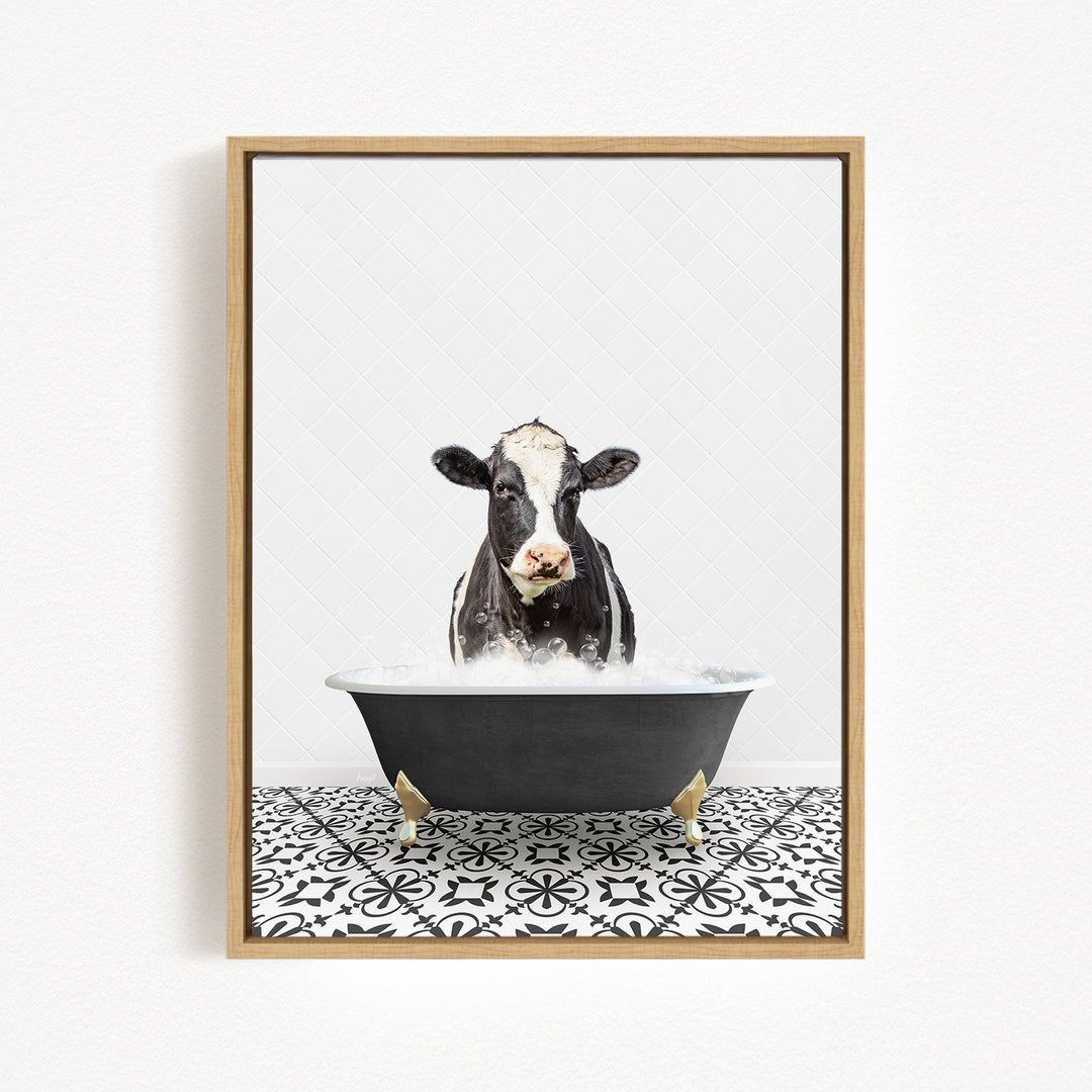 A black and white cow is sitting in a black bathtub filled with water, creating a whimsical and humorous scene.
