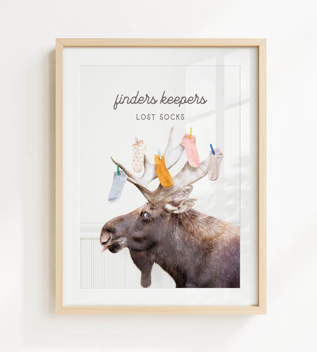 A framed image of a moose with a humorous caption that reads "finders keepers lost socks".