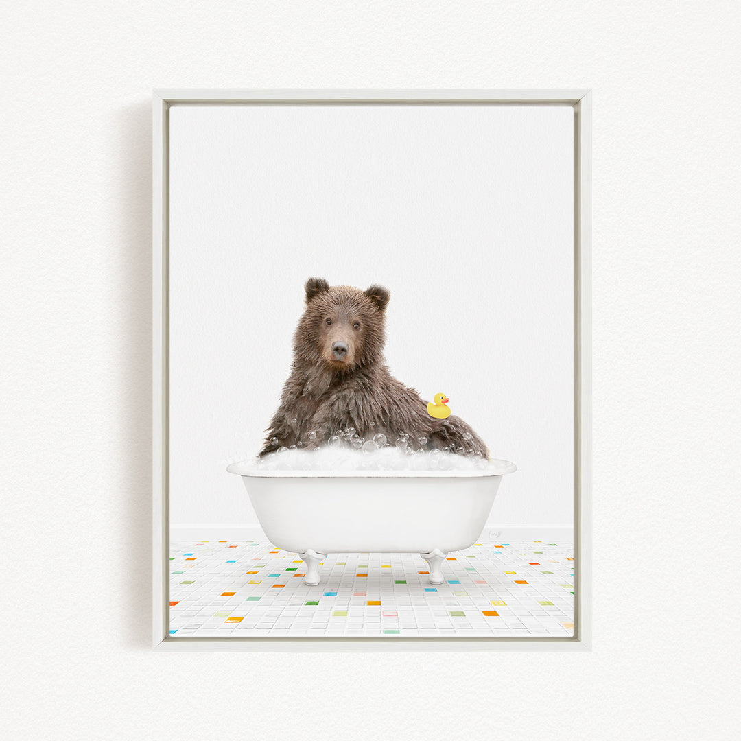 A brown bear sitting in a white bathtub filled with bubbles, with a rubber duck floating on the water.