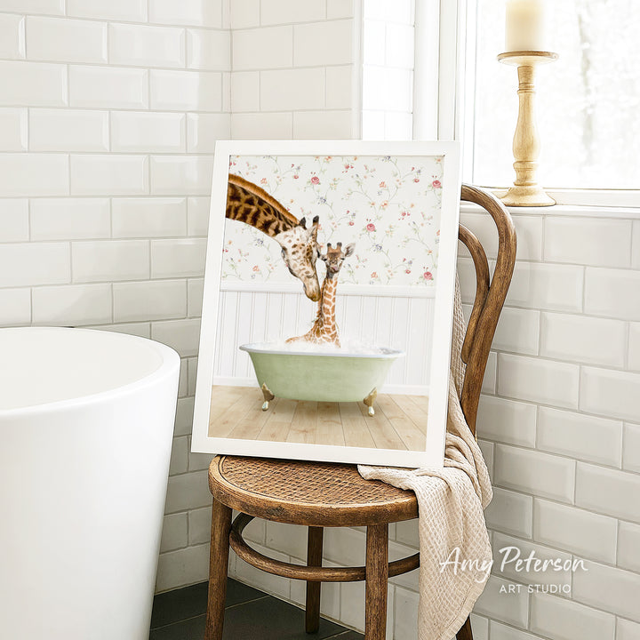 A framed image of two giraffes standing in a bathtub, with one giraffe extending its neck towards the other giraffe.