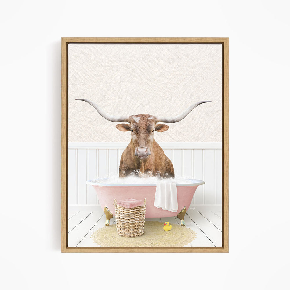 A brown cow with large horns is sitting in a pink bathtub filled with bubbles, surrounded by a yellow rubber duck and a basket.