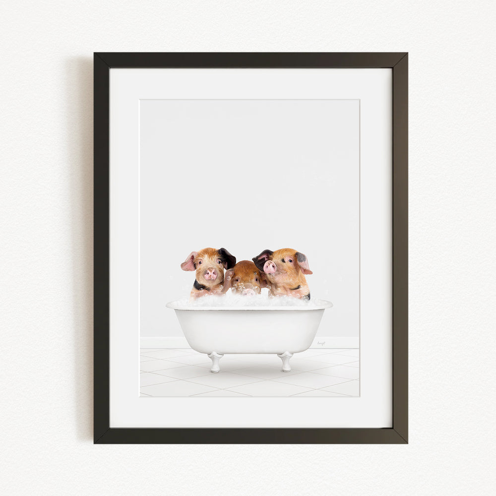 A framed image depicting three adorable pigs sitting in a white bathtub filled with bubbles.