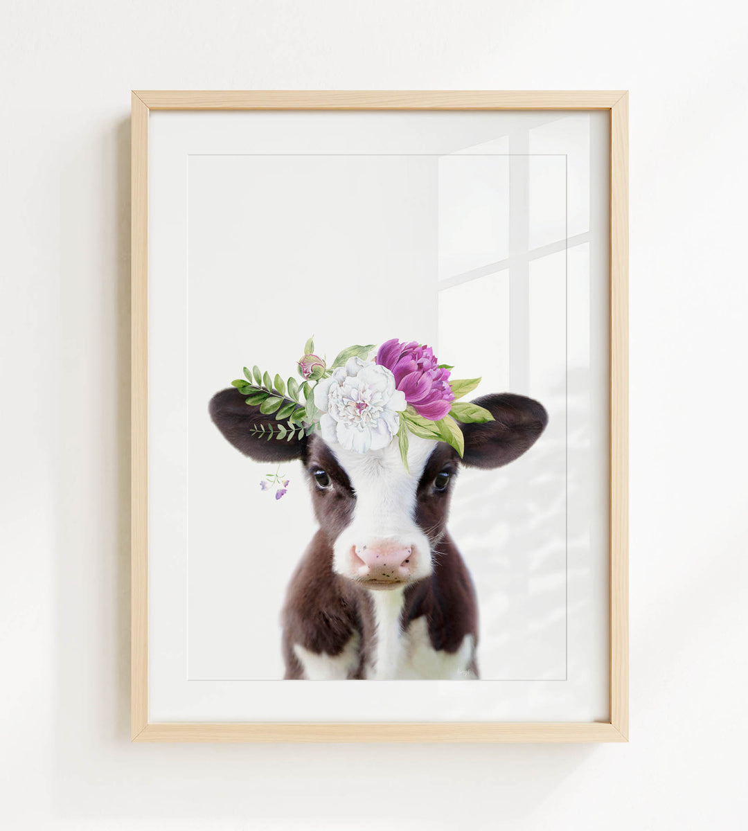 A framed print of a cow wearing a floral crown on its head.